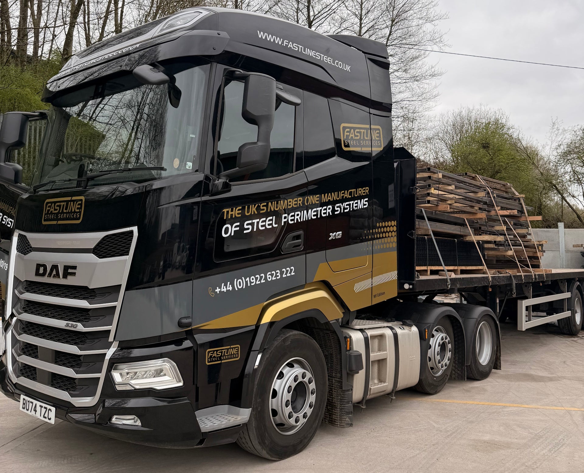 Truck carrying a large load on a road with trees and sky in the background